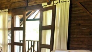 Una habitación de madera con cama, cortinas y vistas al exterior.