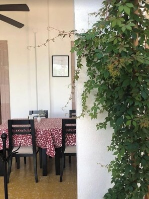 A dining area with a table set for four, chairs, a ceiling fan, and a wall-mounted picture.