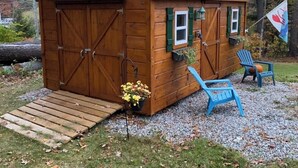 A wooden shed with a green roof, a small porch, and a flag. - Quintessential Cape Vibes in Boothbay (Boothbay)