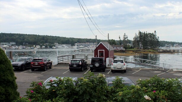 A parking area with cars, a small red building, and a waterfront view. - Quintessential Cape Vibes in Boothbay (Boothbay)