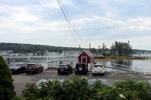 A parking area with cars, a small red building, and a waterfront view. - Quintessential Cape Vibes in Boothbay (Boothbay)