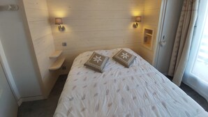 A bedroom with a bed, two wall-mounted lamps, a nightstand, and a small shelf. - Ski in ski out Apartment LYS ORANGES, for your holidays in MEGEVE, 4 p (Megève)