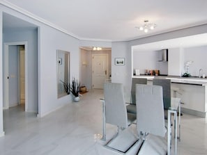 Una cocina moderna con una isla central, sillas tapizadas en gris y un espejo grande sobre la encimera.