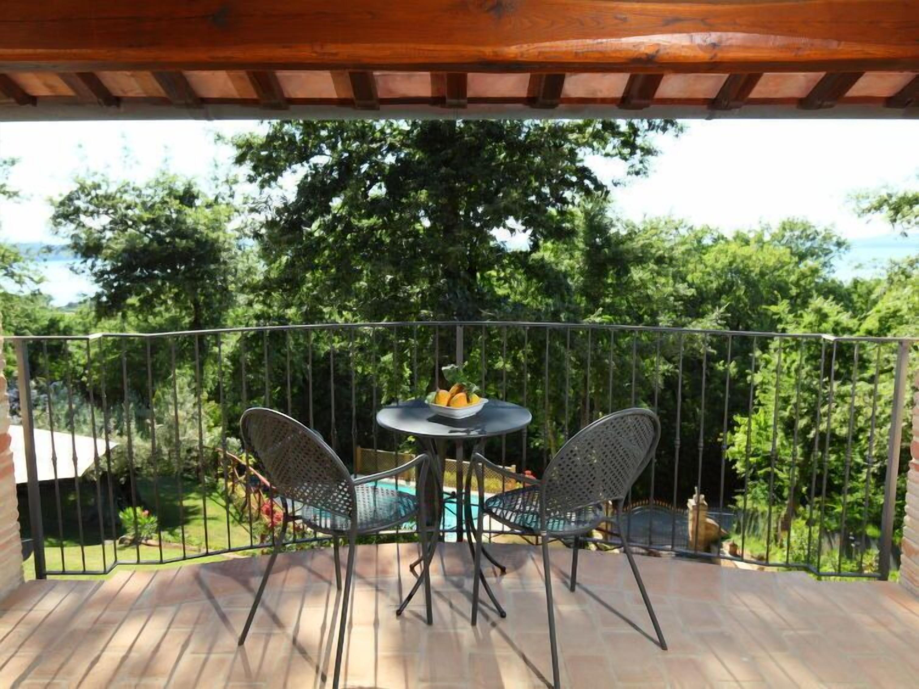 Een overdekt buitengebied met een tafel en twee stoelen, omringd door een metalen hekwerk.