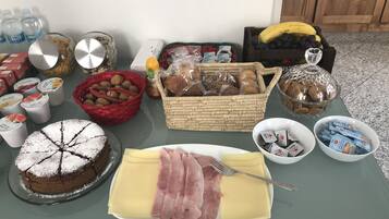 Ein Tisch mit verschiedenen Speisen, darunter Kuchen, Käse, Schinken und Brot.