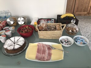 A table with various food items including a cake, cheese, ham, and bread. - La Casa di Anna (Delebio)