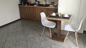 A small kitchenette with a coffee maker, kettle, and toaster. There is a wooden table with two white chairs. - La Casa di Anna (Delebio)