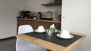A small, modern kitchen with wooden cabinets, a coffee maker, and a kettle on the counter. - La Casa di Anna (Delebio)