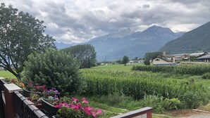 A balcony with a view of a green field, mountains, and a village in the background. - La Casa di Anna (Delebio)