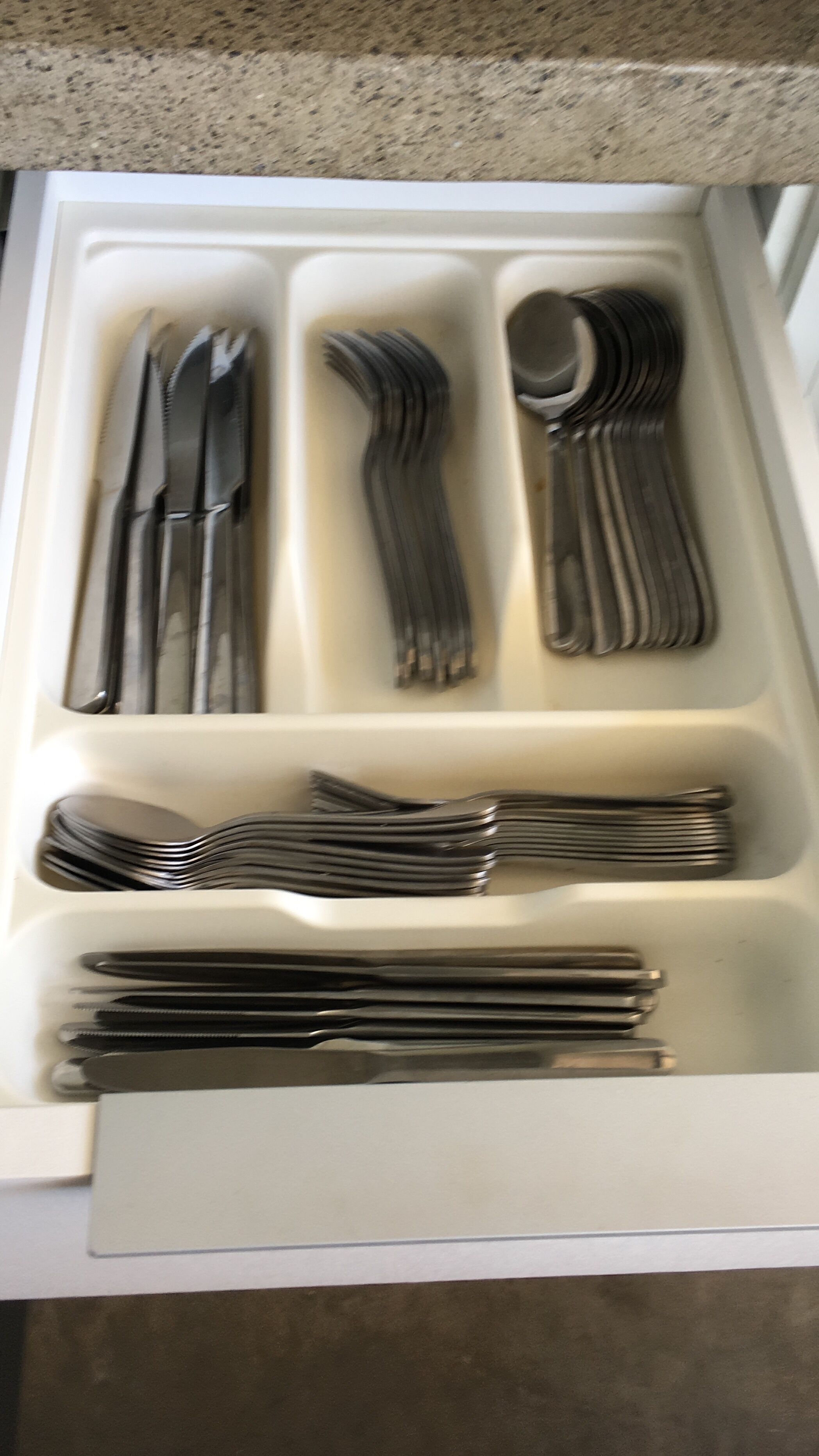 A drawer containing neatly arranged cutlery including forks, knives, and spoons.