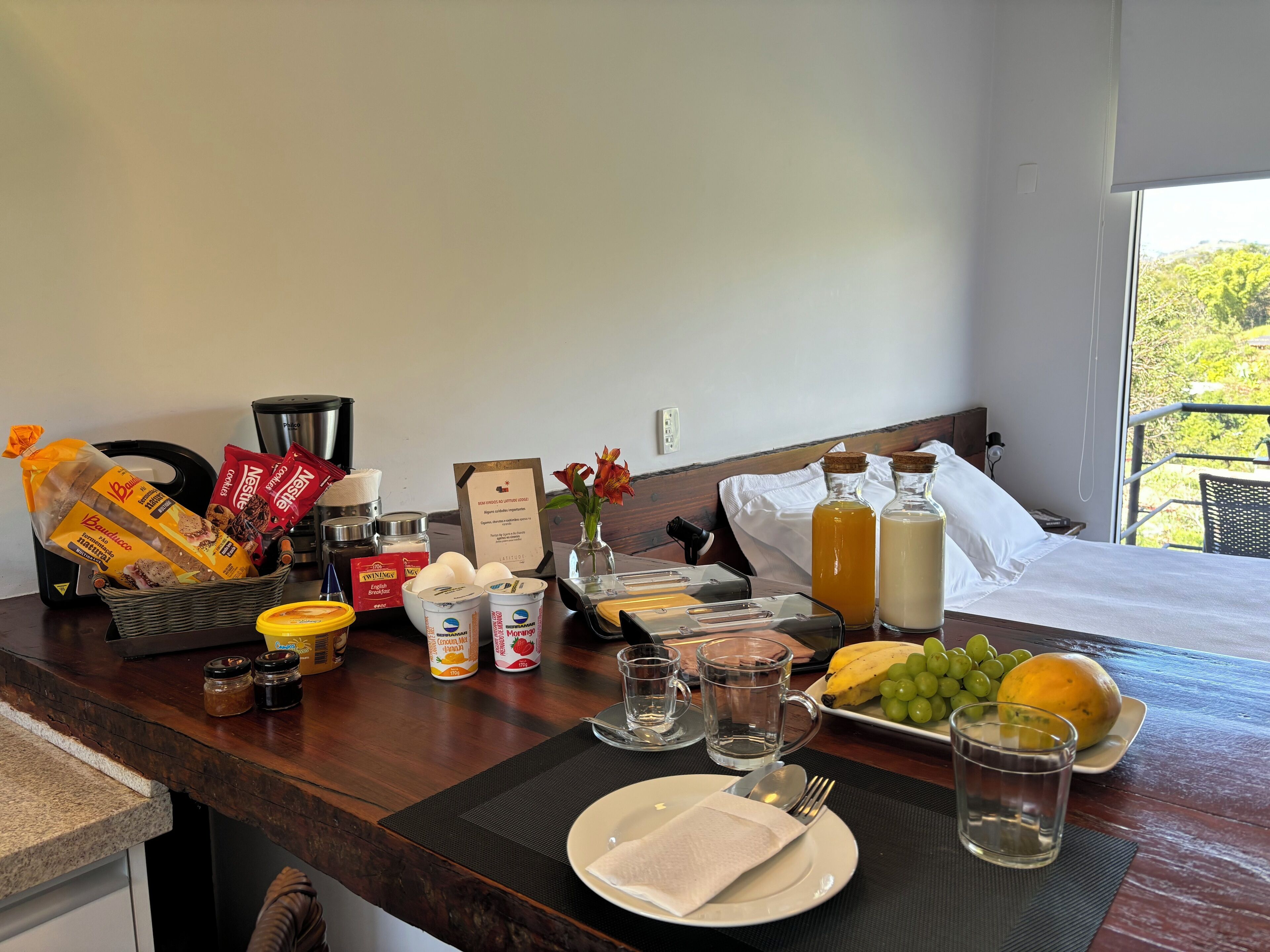 A breakfast setup with bread, condiments, milk, and fruit on a wooden table.