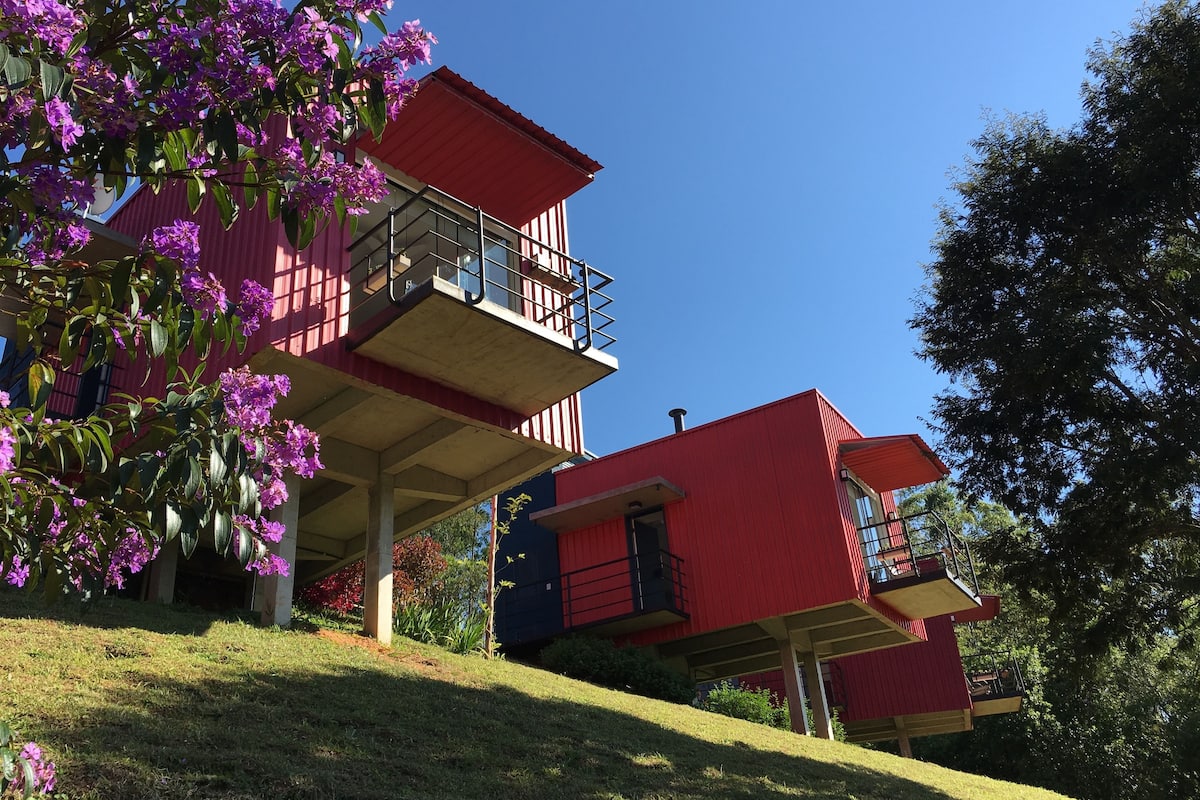 Ein rotes Gebäude mit einem Balkon und einem Baum mit violetten Blüten.