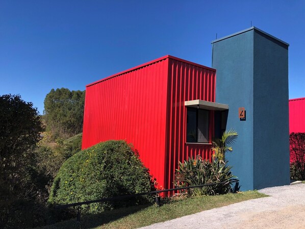 Um edifício moderno com fachada em vermelho e azul, uma pequena janela e uma placa com o número 4.