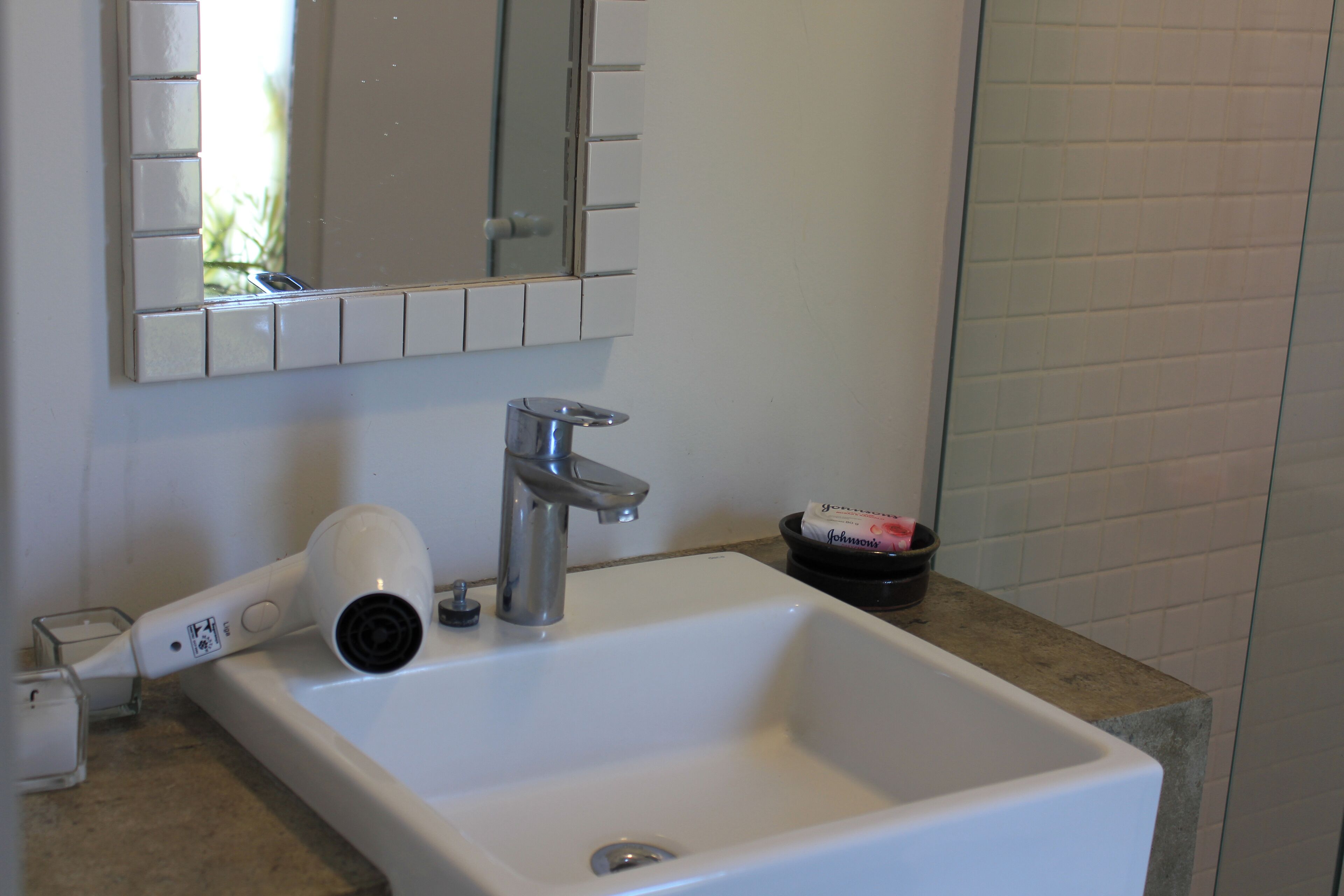 Un baño con lavamanos blanco, espejo y secador de pelo.
