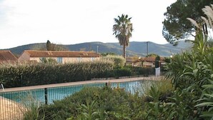 Une piscine entourée d’une végétation luxuriante, avec une chaîne de montagnes en toile de fond.