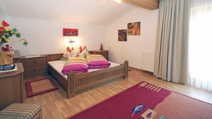 Een knus slaapkamer met een houten bed, een nachtkastje, een dressoir en een raam met gordijnen.