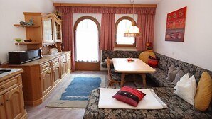 Een ruimtelijk ingerichte leefruimte met kitchenette, eethoek en zithoek.