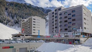 A modern hotel with multiple floors, a parking area, and a view of snow-covered mountains. - Rosablanche B72 by Interhome (Siviez-Nendaz)