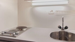 A kitchen with a stainless steel sink, a built-in stove, and a wall-mounted light above the counter. - Rosablanche B72 by Interhome (Siviez-Nendaz)