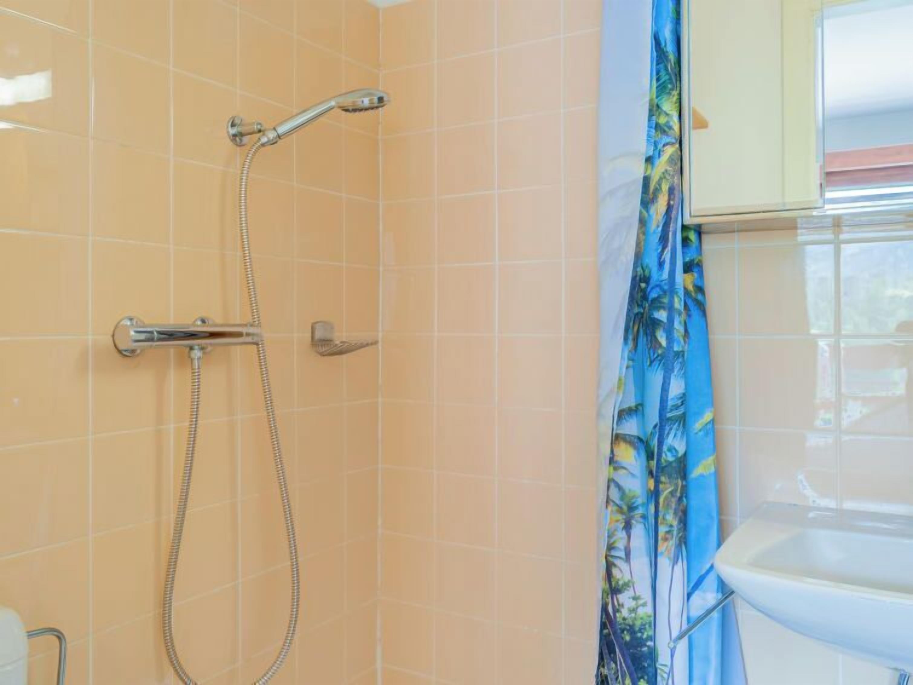 A bathroom with a shower, tiled walls, and a sink.