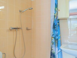 Ein Badezimmer mit Dusche, gefliesten Wänden und Waschbecken.