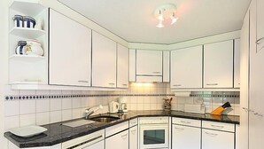 Een moderne keuken met witte kasten, een zwart aanrecht en een betegelde spatwand.