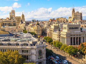 Un paysage urbain avec des bâtiments historiques, dont un arc de triomphe imposant et un grand bâtiment orné de colonnes.