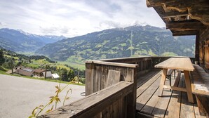 A wooden deck with a table and benches overlooking a mountainous landscape.