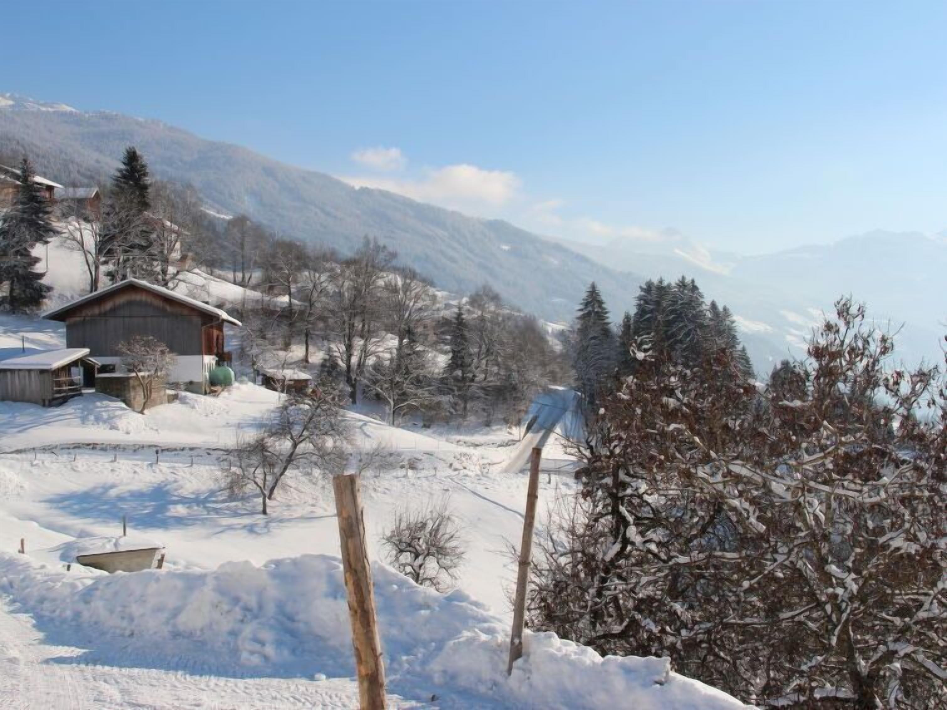 Un paysage enneigé avec une cabane en bois et une montagne en arrière-plan.