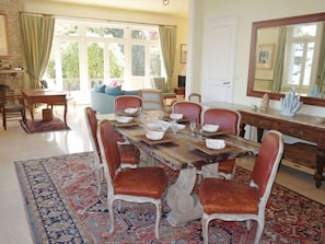 A dining area with a large wooden table set for six, surrounded by red upholstered chairs.