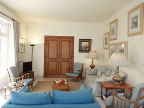 A living room with a blue sofa, a wooden cabinet, a television, and a lamp.