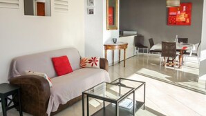 Sala de estar moderna com sofá, mesa de centro e área de jantar.