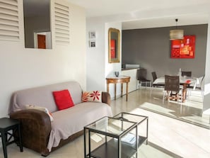 A modern living room with a sofa, coffee table, and dining area.