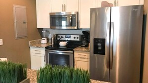 Una cocina moderna con electrodomésticos de acero inoxidable, armarios blancos y encimeras de granito.