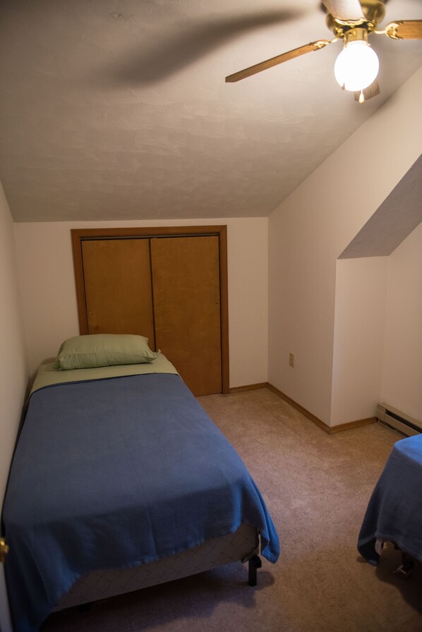 Une chambre à coucher avec un lit, un ventilateur de plafond et une armoire.
