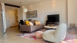 A modern living room with a sofa, a round coffee table, a television, and a ceiling fan.