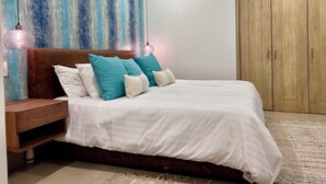 A bedroom with a bed, a nightstand, a wooden wardrobe, and a textured wall.