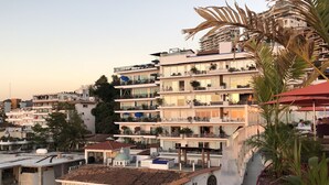 A multi-story hotel with balconies, outdoor seating, and a rooftop terrace.