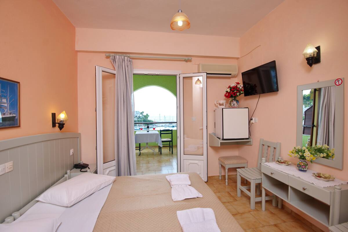 A hotel room with a bed, a desk, a chair, a TV, and a window with curtains.