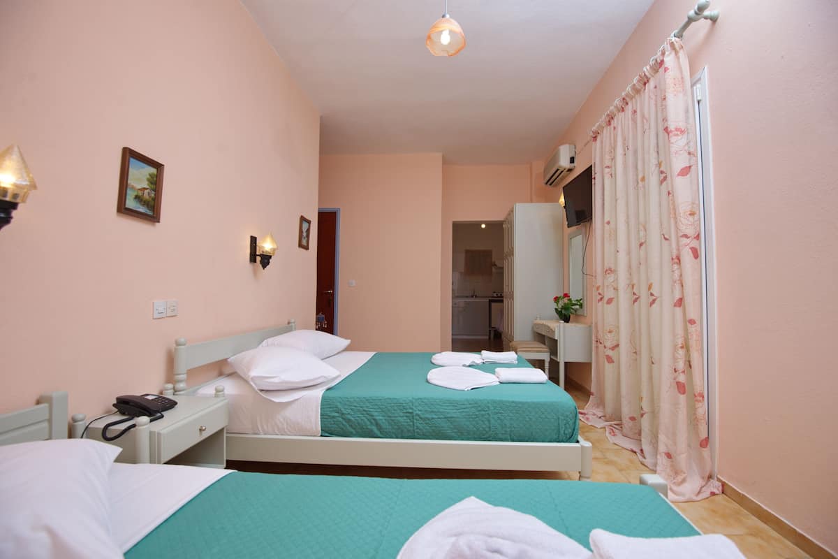 A hotel room with two beds, a small desk, a telephone, and a mirror.