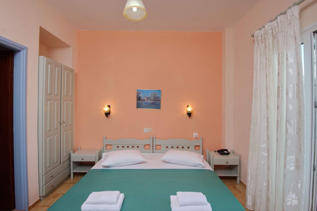 A bedroom with a bed, two bedside tables, a wardrobe, and a painting on the wall.