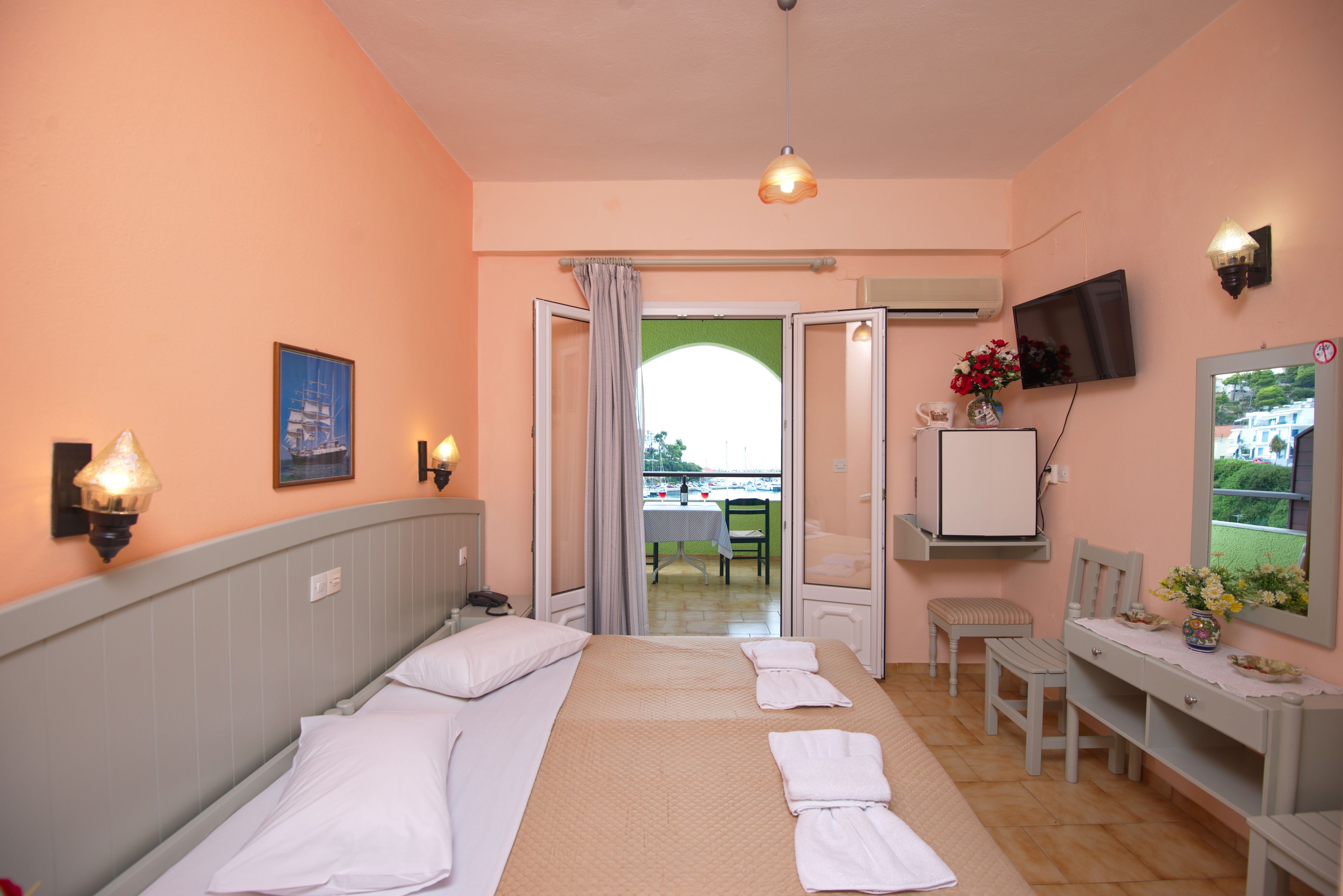 A hotel room with a bed, a desk, a chair, a TV, and a window with a view of the outside.