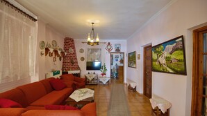 A living room with a sofa, a TV, and a painting on the wall. - Haravgi Hotel (Alonissos)
