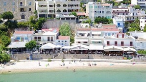 A coastal town with buildings along the beach, including a restaurant with outdoor seating. - Haravgi Hotel (Alonissos)