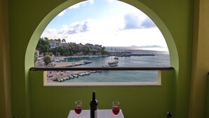 A room with a view of a marina, a bottle of wine, and two glasses on a table. - Haravgi Hotel (Alonissos)