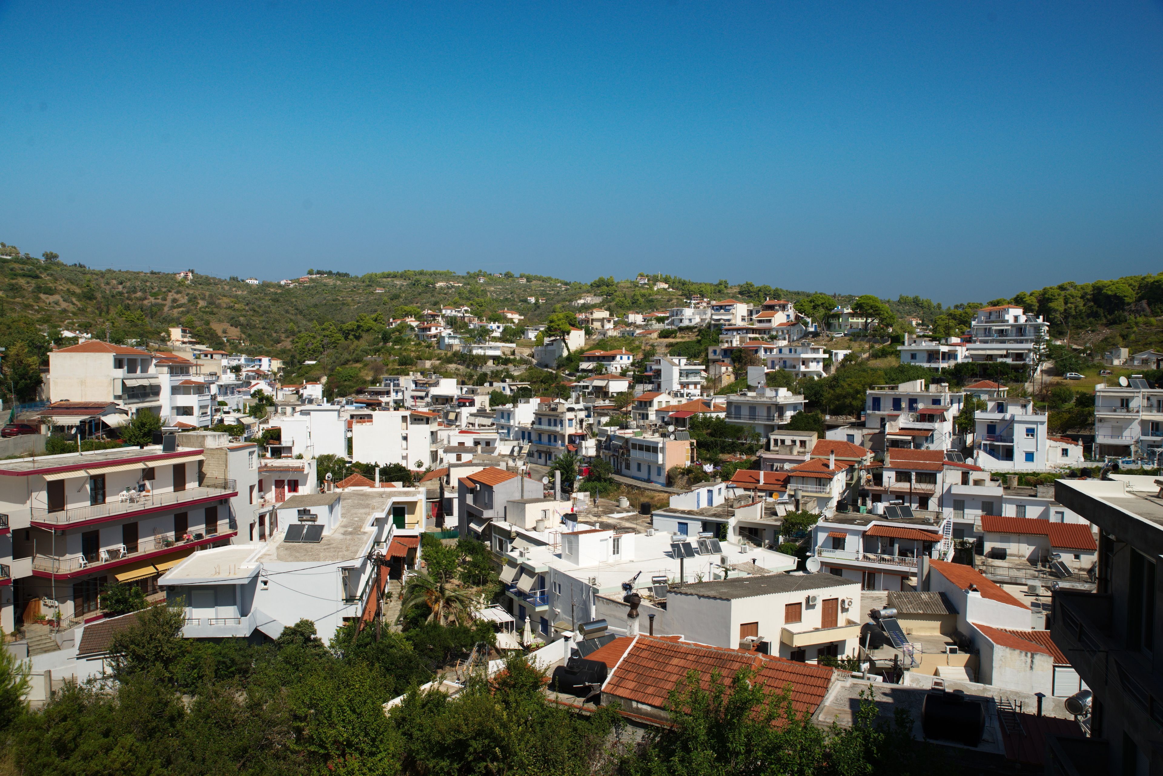 Zona residencial densa con edificios de varios pisos, algunos con balcones, y un terreno montañoso al fondo.