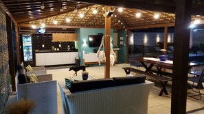 Un espace extérieur aménagé en terrasse, avec une cuisine, des sièges et un hamac suspendu.