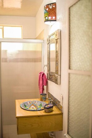 A bathroom with a wooden vanity, a decorative mirror, and a colorful tile backsplash.