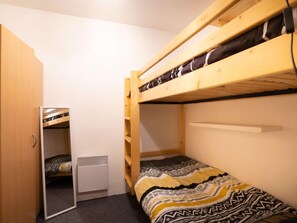 A small, compact room with two bunk beds, a wardrobe, and a small desk. - Arcelle 216 by Interhome (Val Thorens)