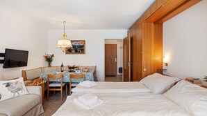 Ein Hotelzimmer mit Bett, Sofa, Esstisch mit Stühlen, Fernseher und Holzschrank.